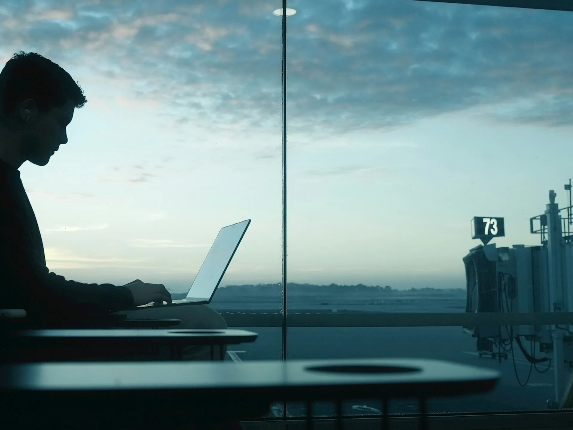 A traveller working by an airport window at sunrise